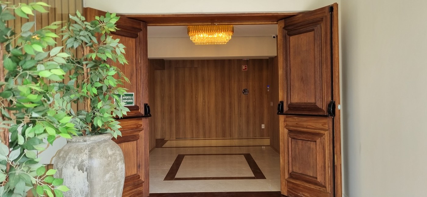Entrada do Flat Care com portas de madeira e recepção